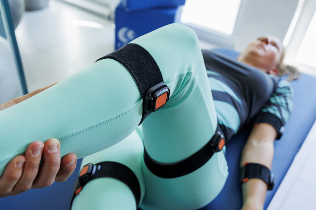 Kobieta wykonuje ćwiczenie z czujnikami na nodze leżąc na leżance